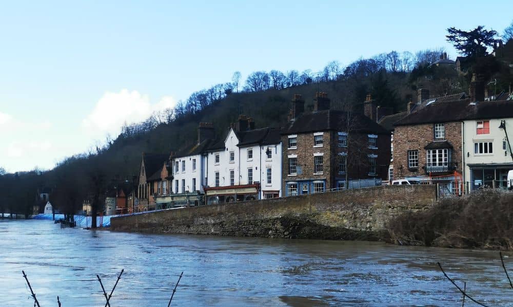 Riverfront homes near rising water showing flood risk for residential properties, illustrating the need for a flood elevation survey
