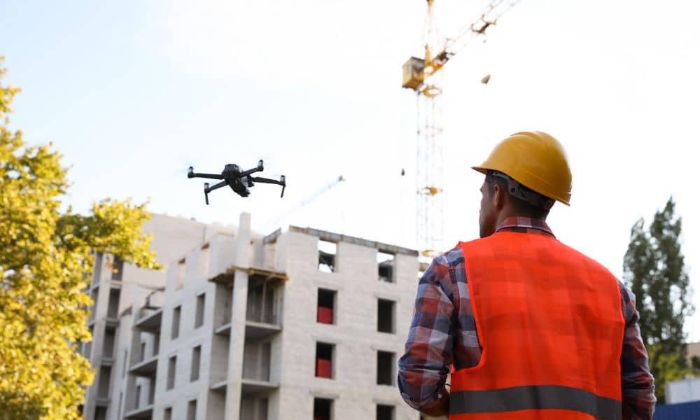 An engineer uses a drone for an unmanned aerial system survey above an active construction site