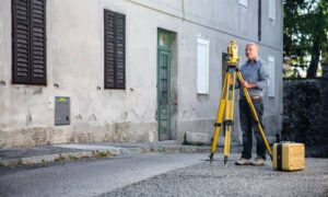 Surveyor standing outdoors with total-station - ALTA SURVEY Orlando Surveyor using professional equipment to measure property lines in a residential area for a boundary survey