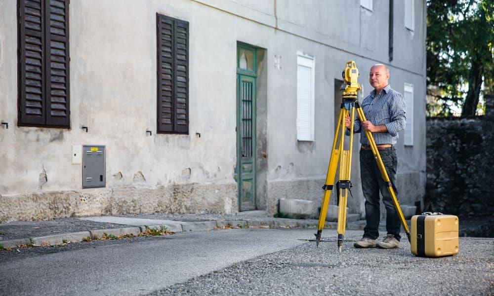 Surveyor using professional equipment to measure property lines in a residential area for a boundary survey