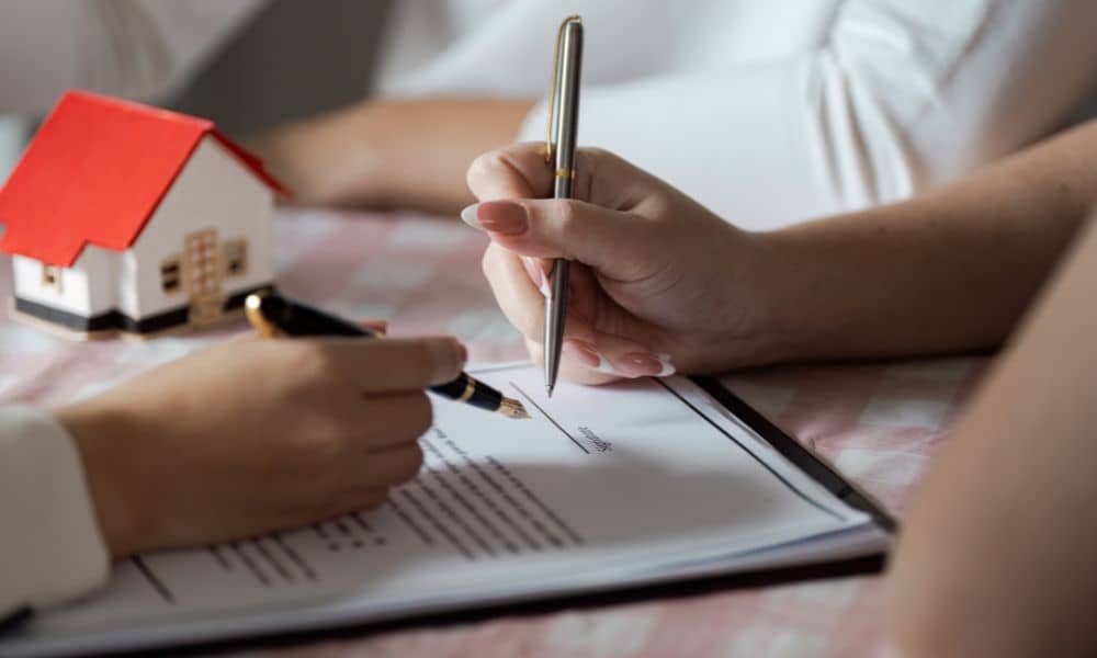 Homebuyer and title officer reviewing an alta land title survey and signing property documents during a real estate closing
