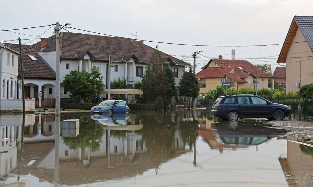 Flooded residential street with cars and homes showing why a FEMA Elevation Certificate is important for homeowners
