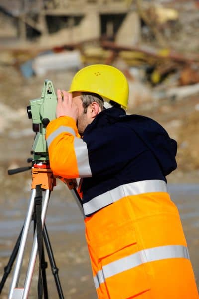 Licensed land surveyor using equipment to measure property elevation for a FEMA Elevation Certificate
