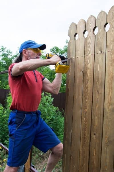 Homeowner repairing wooden fence after property line mistake caused by skipping a construction staking survey


