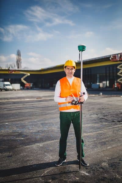 A surveyor using a GNSS receiver on a construction site to check accuracy during conditions that can affect drone surveying measurements