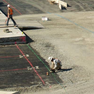 Construction surveyor checking layout lines and grade markings on an active job site