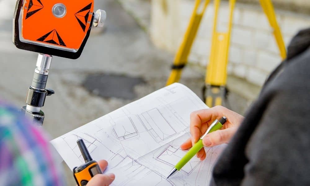 Surveyors reviewing a site plan and verifying property boundaries during an ALTA land survey
