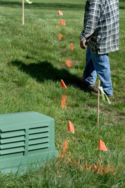 Local surveyor marking property boundary lines with flags on residential land