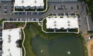 Aerial view of buildings, parking lots, roads, and a pond, showing site features considered when planning stormwater drainage